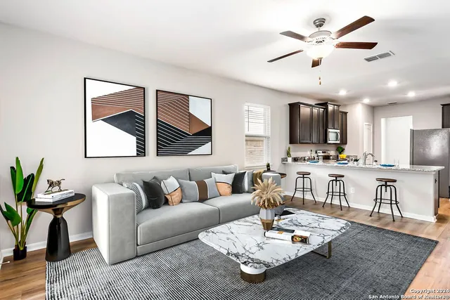 a living room with furniture kitchen view and a wooden floor