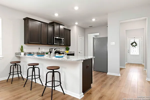 a kitchen with stainless steel appliances granite countertop wooden floors a refrigerator and a stove