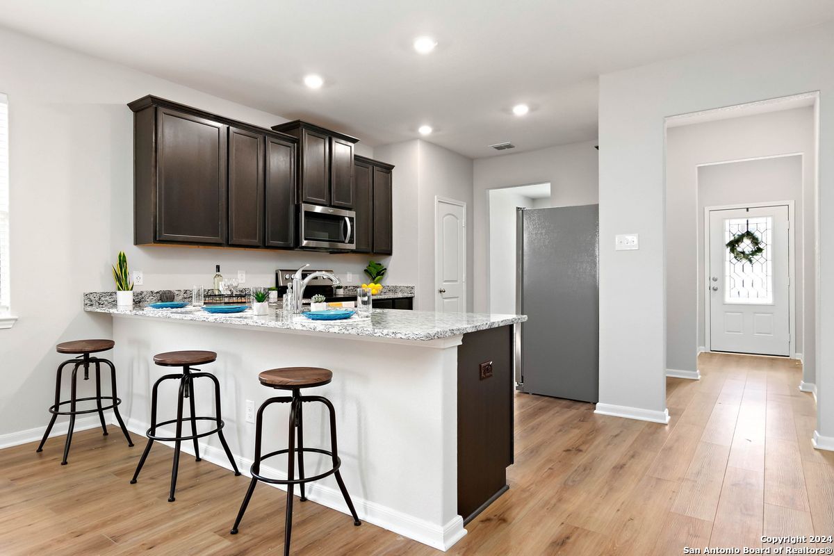9219 Bennett Forest Converse, TX 78109 - Photo 9 of 23 a kitchen with stainless steel appliances granite countertop wooden floors a refrigerator and a stove