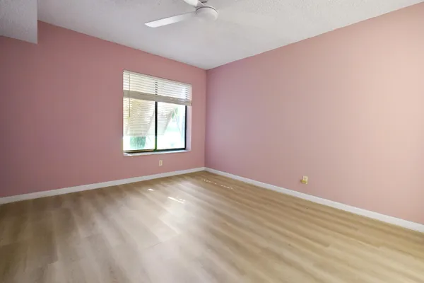 an empty room with windows and fan