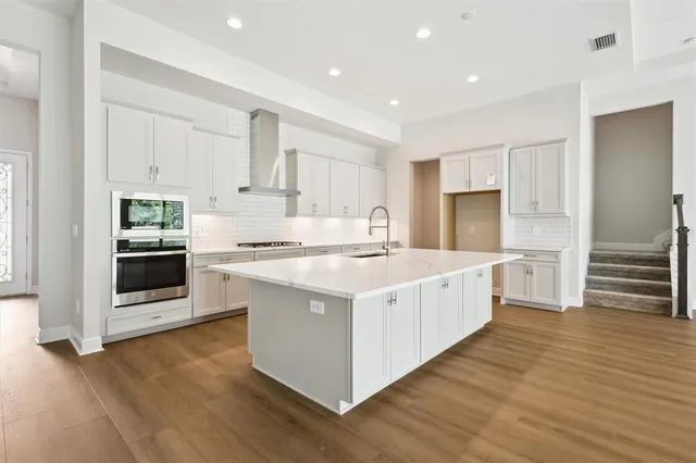 a kitchen with stainless steel appliances wooden floor sink and wooden cabinets