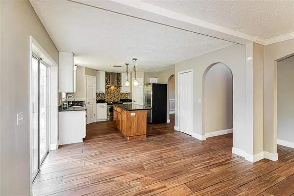 a kitchen with granite countertop a refrigerator a stove top oven and wooden floor