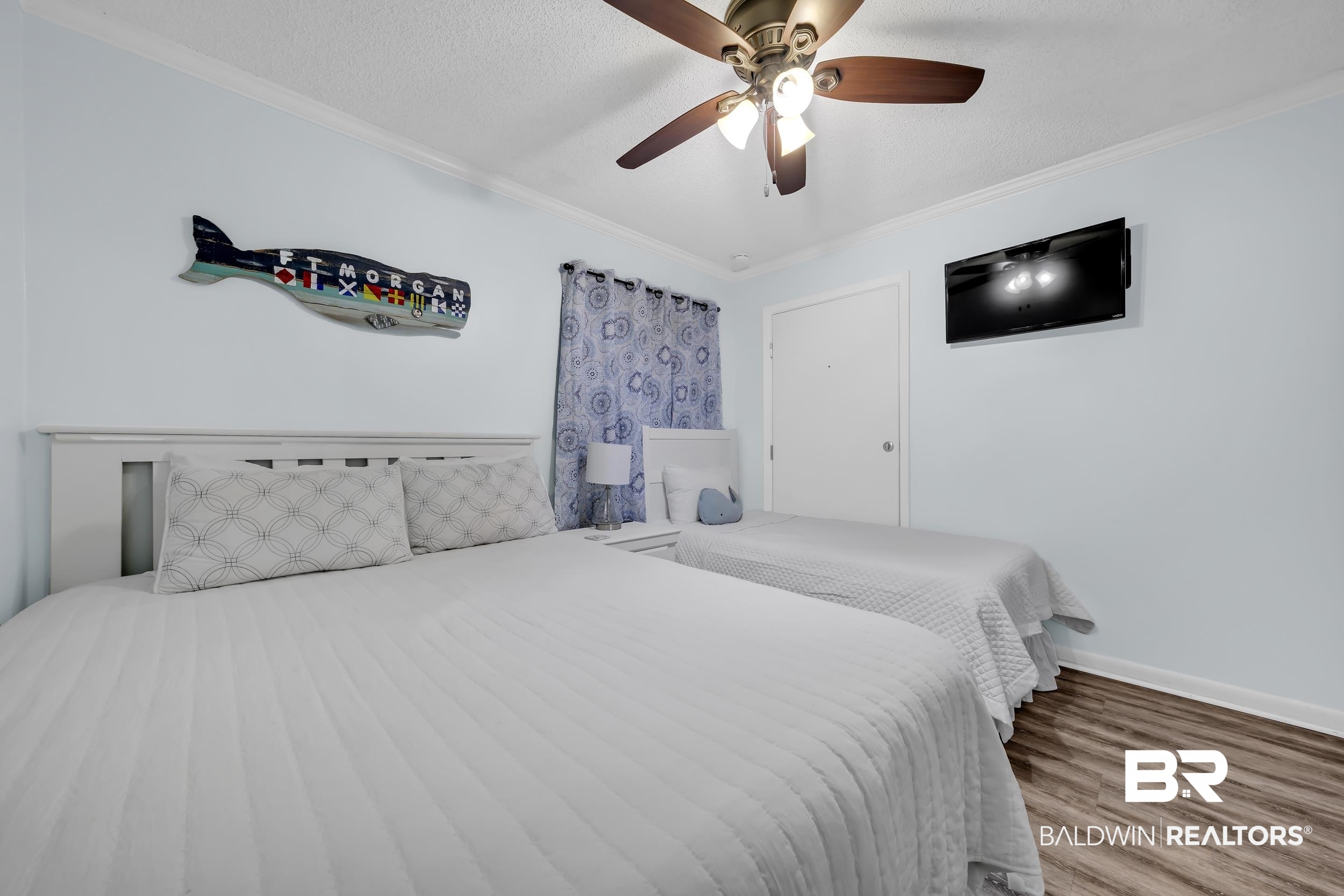 400 Plantation Road, Unit 2118 Gulf Shores, AL 36542 - Photo 20 of 59 Spacious room featuring light blue walls, wood-finish flooring, white crown molding, and a ceiling fan with integrated lighting