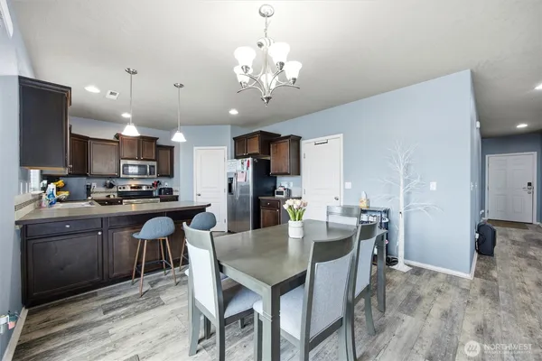 a kitchen with a dining table chairs stainless steel appliances and cabinets