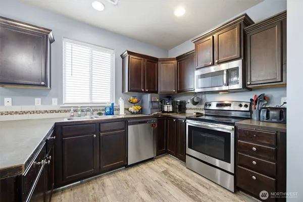a kitchen with granite countertop a sink cabinets stainless steel appliances and a window
