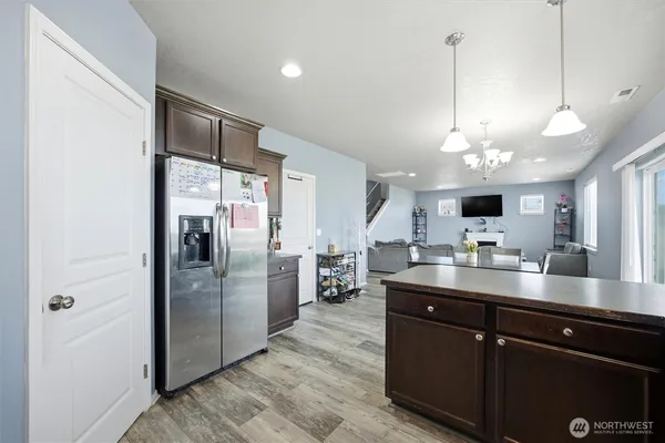 a kitchen with stainless steel appliances granite countertop a refrigerator a sink dishwasher a oven and a large island with wooden floor