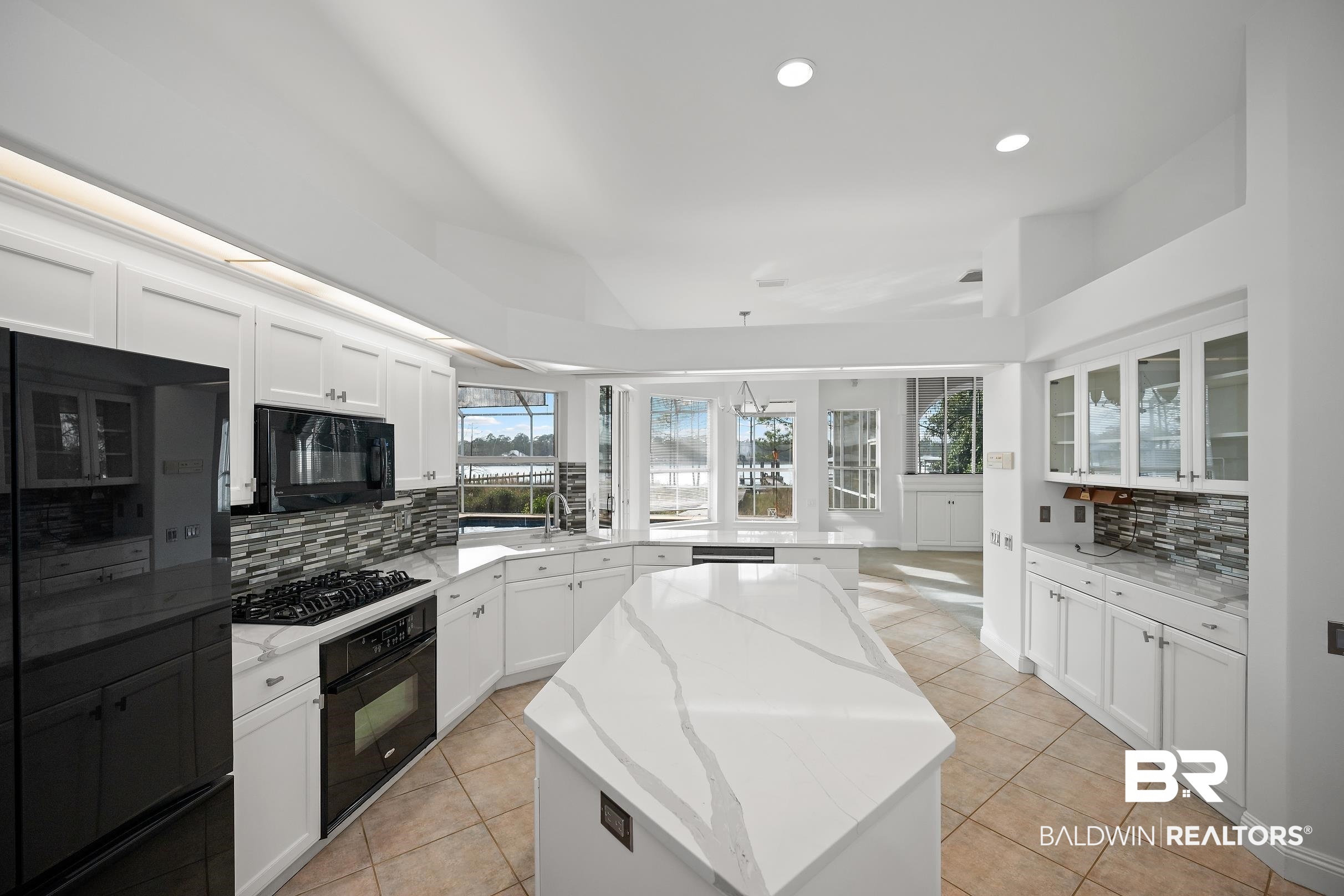 8591 Bay Harbor Road Elberta, AL 36530 - Photo 15 of 56 Kitchen with tasteful backsplash, light tile patterned flooring, a center island, white cabinetry, and recessed lighting