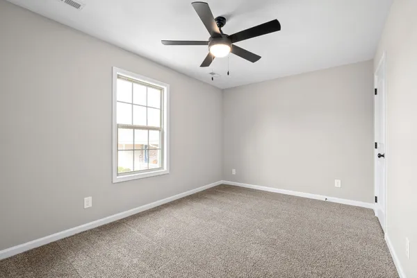 an empty room with a window and a fan