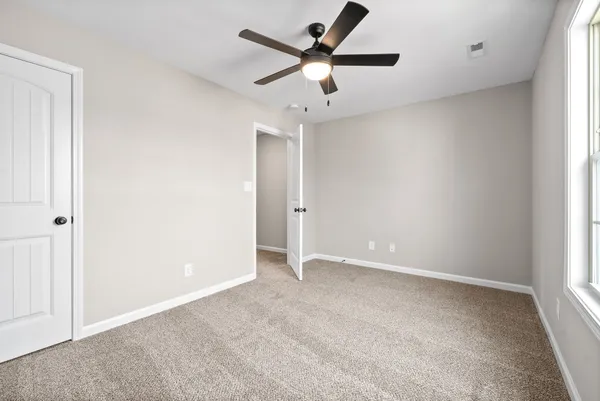 an empty room with ceiling fan and window