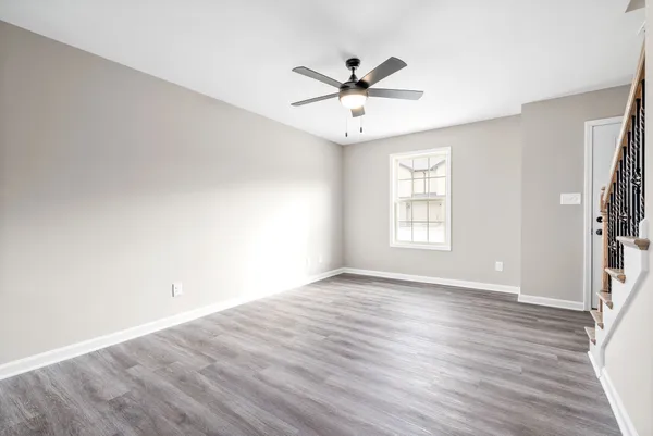 an empty room with wooden floor fan and windows