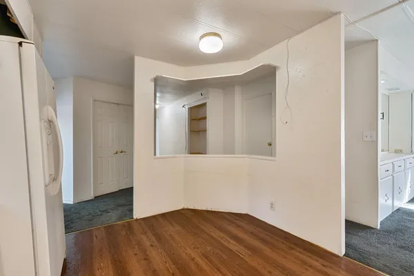 a view of a hallway with wooden floor and a bathroom