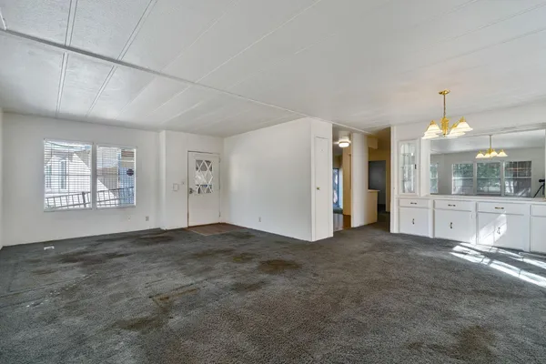 a view of an empty room with kitchen and window