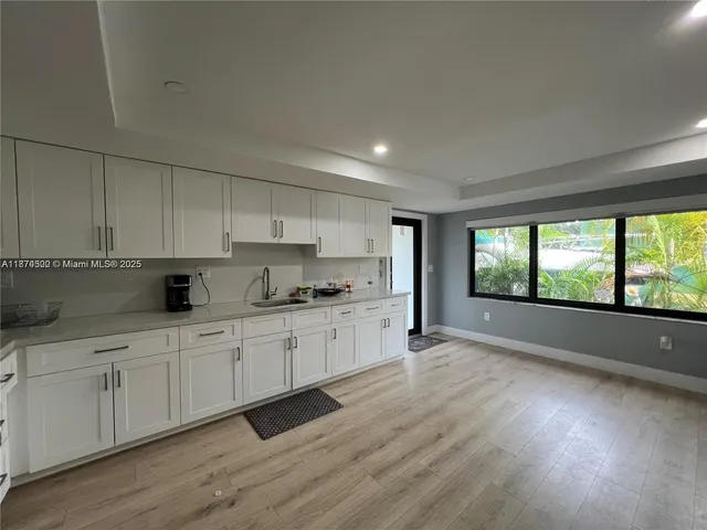 a large white kitchen with a large window a sink and white appliances