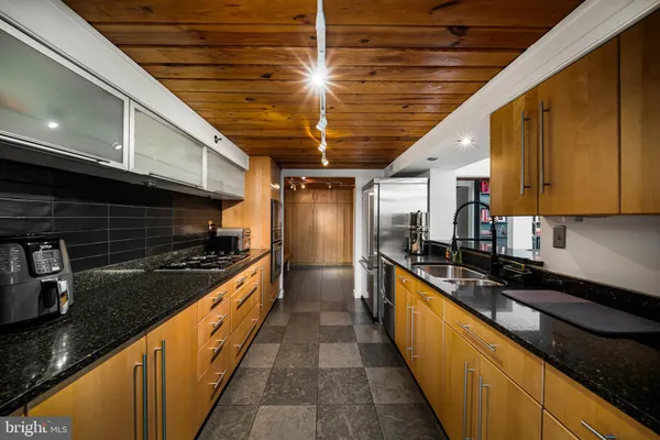 a large kitchen with stainless steel appliances wooden cabinets table and chairs
