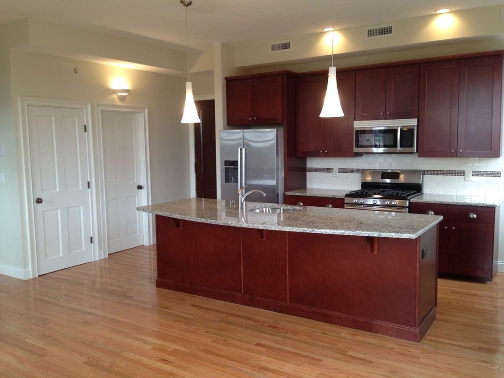 191 Main Street, Unit 2B Gloucester, MA 01930 - Photo 9 of 20 a kitchen with stainless steel appliances granite countertop a stove a sink and a refrigerator