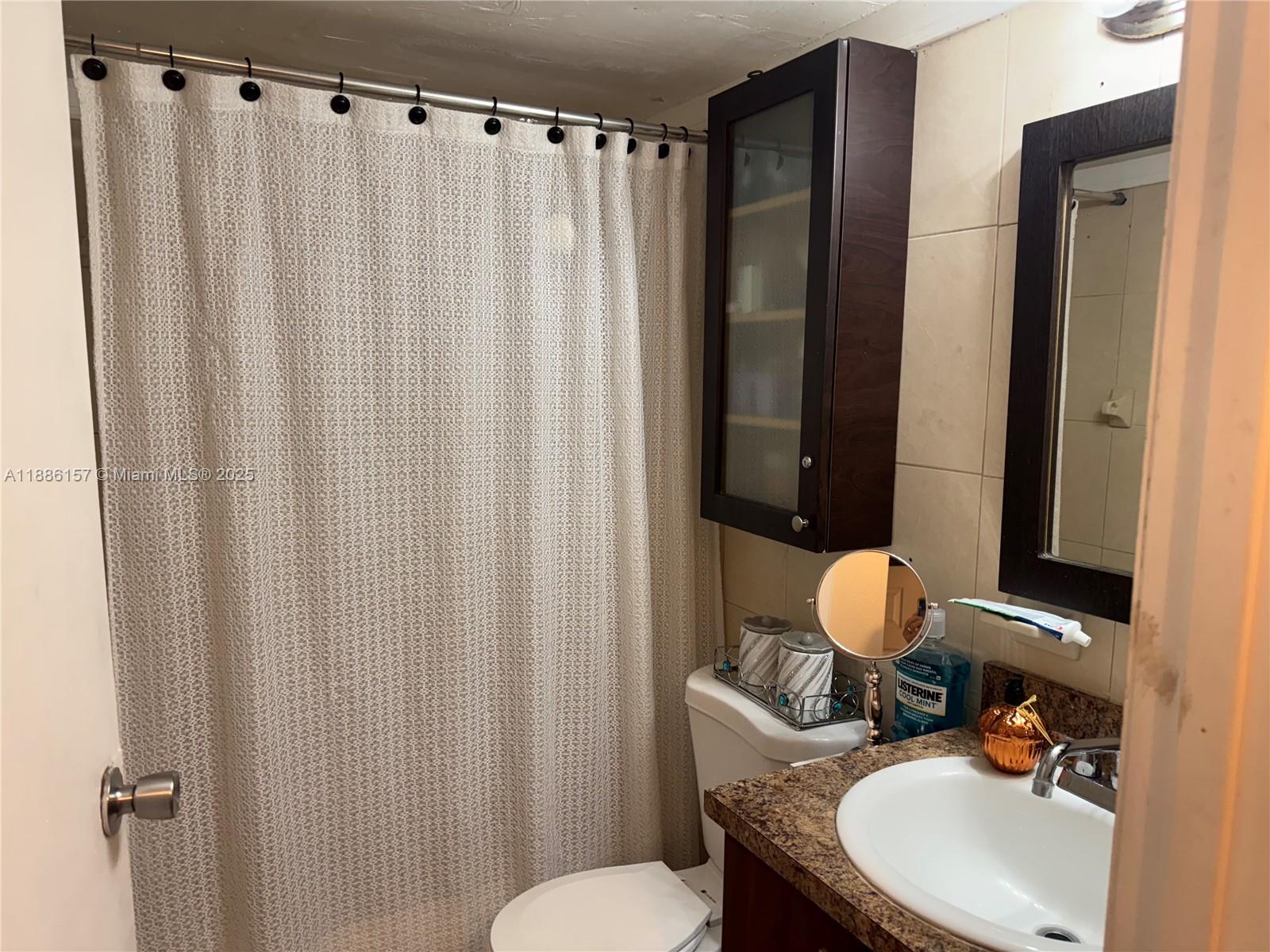 1825 West 56th Street, Unit 107 Hialeah, FL 33012 - Photo 5 of 6 a bathroom with a sink toilet and shower curtain