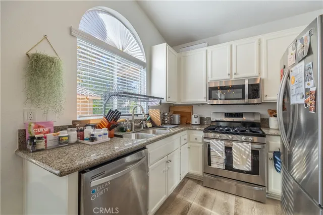 a kitchen with granite countertop a sink a window and cabinets