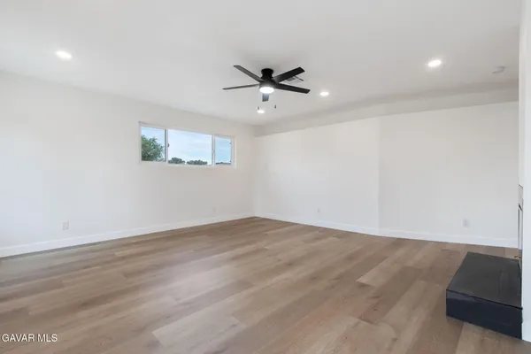 an empty room with wooden floor a ceiling fan and a window