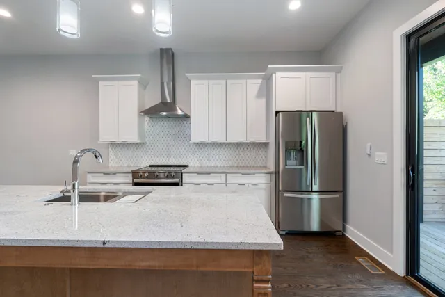 a kitchen with stainless steel appliances granite countertop a refrigerator a sink and a stove