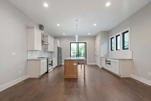 a large kitchen with stainless steel appliances granite countertop a stove a sink dishwasher and a oven with white cabinets