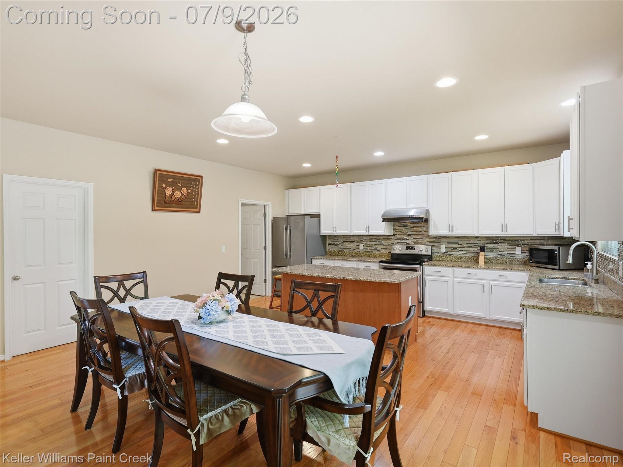 846 Monterey Ln. Rochester, MI 48307 - Photo 14 of 52 Open-concept kitchen and dining area featuring warm wood-finish flooring, white cabinetry, and granite countertops