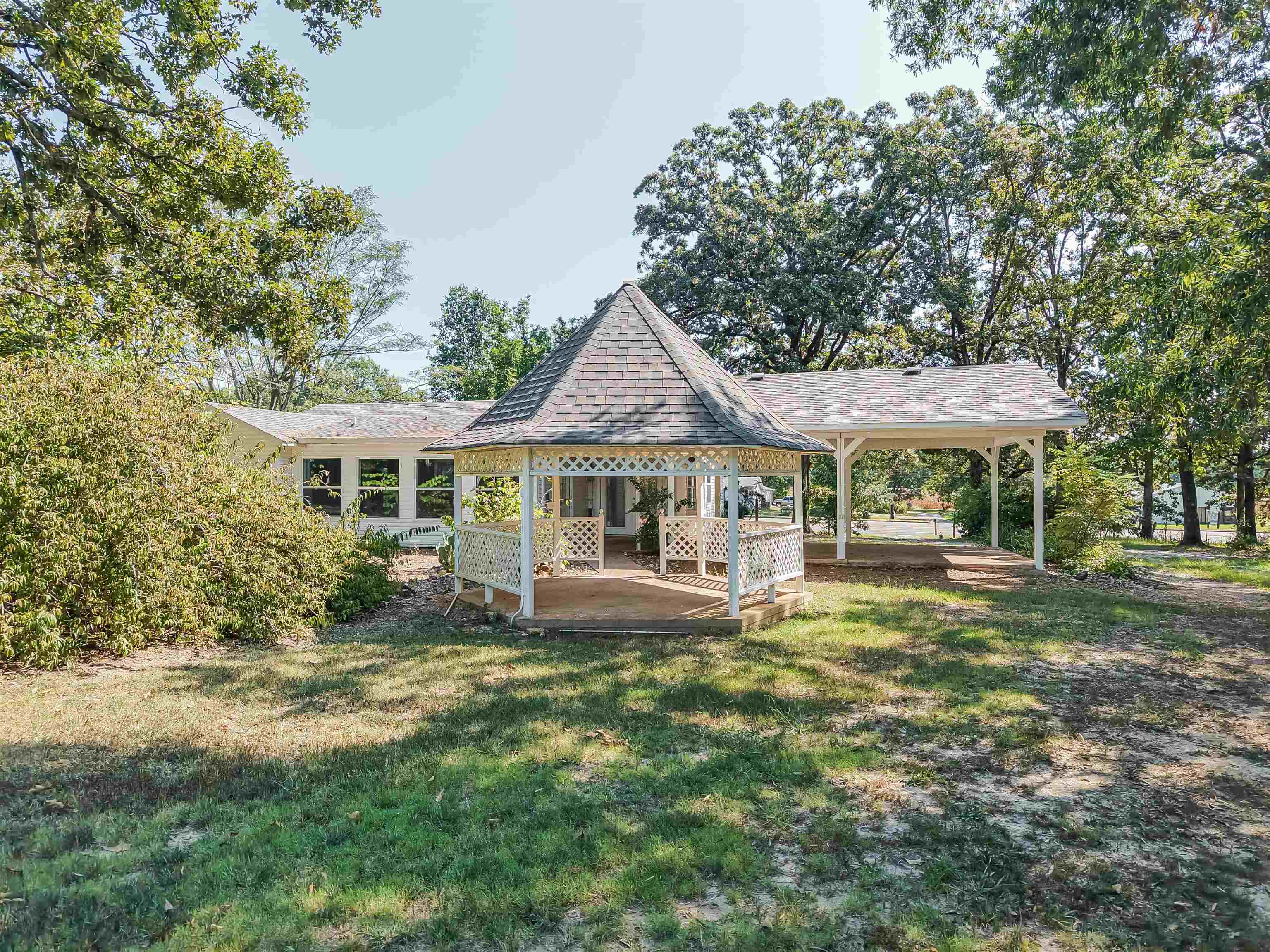 7437 Highway 45 Ramer, TN 38367 - Photo 6 of 36 Backyard featuring a gazebo with a shingled roof, an attached covered patio, mature trees, and a residential structure with multiple windows
