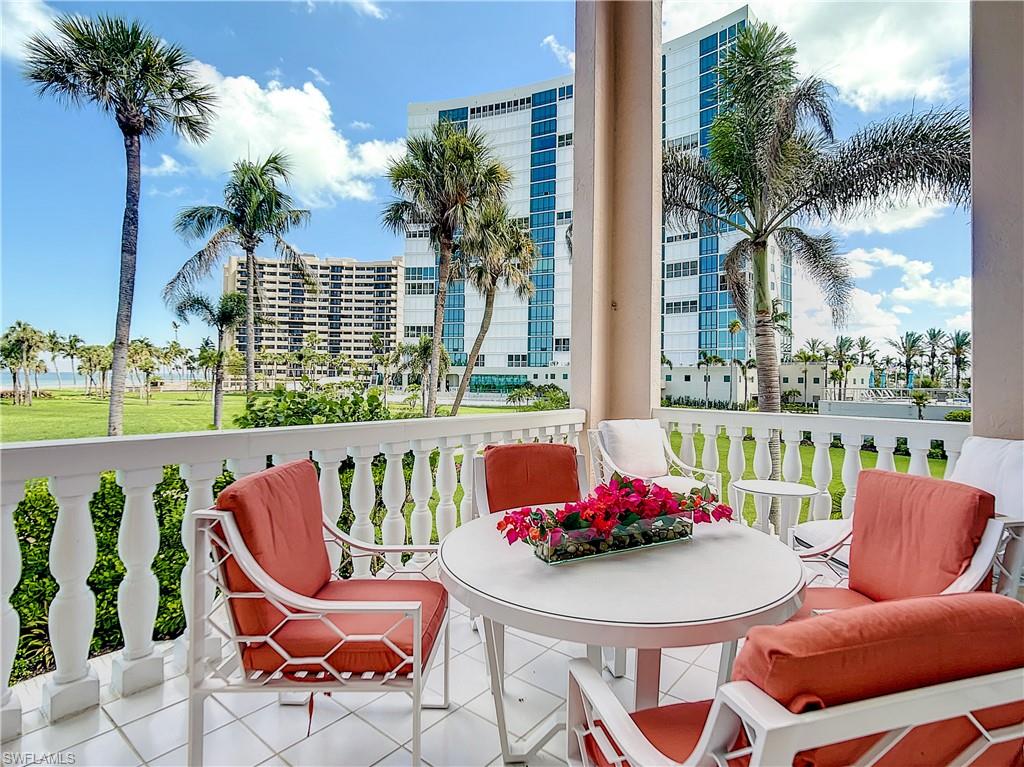 21 Casa Mar Lane, Unit 21 Naples, FL 34103 - Photo 4 of 47 a balcony with table and chairs potted plants and palm trees