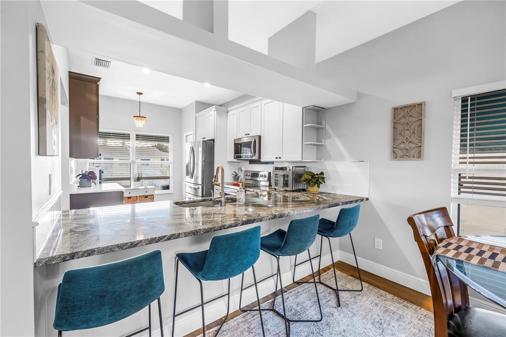 6311 99th Way North, Unit 11A St. Petersburg, FL 33708 - Photo 13 of 52 a kitchen with stainless steel appliances granite countertop a stove top oven a sink a dining table and chairs