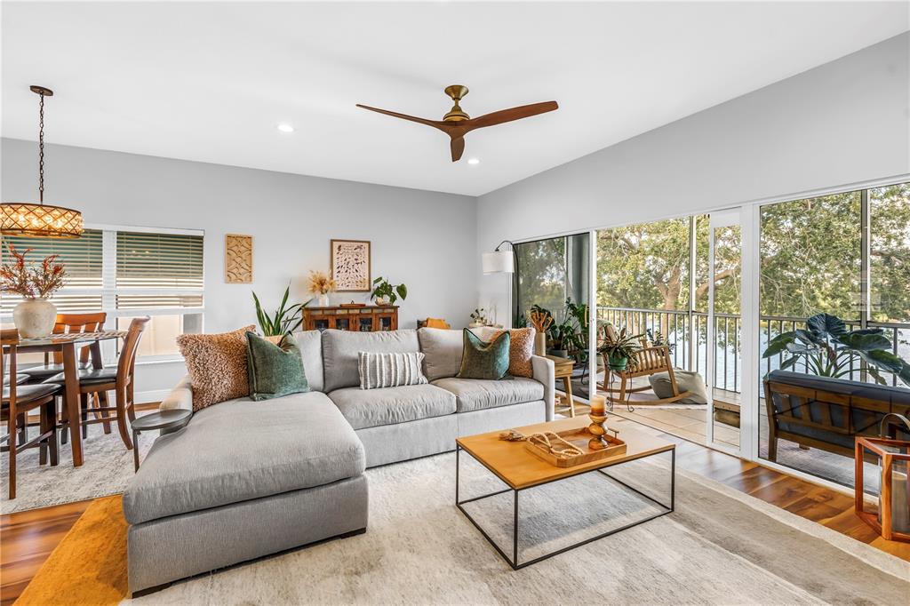 6311 99th Way North, Unit 11A St. Petersburg, FL 33708 - Photo 9 of 52 a living room with furniture a flat screen tv and a floor to ceiling window