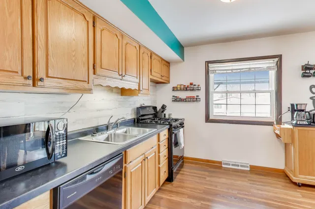 a kitchen with stainless steel appliances granite countertop a sink a stove and a wooden floors