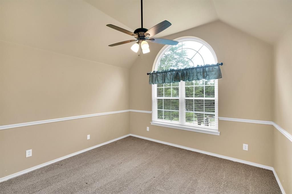 1907 Timber Ridge Court Cedar Hill, TX 75104 - Photo 22 of 30 Vaulted ceiling room featuring a large arched window, ceiling fan with light fixture, neutral-toned carpeting, and chair rail molding