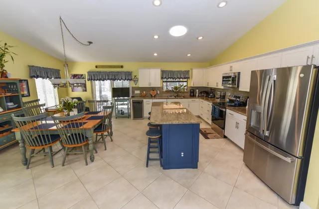 a kitchen with stainless steel appliances a refrigerator a stove a sink a dining table and chairs