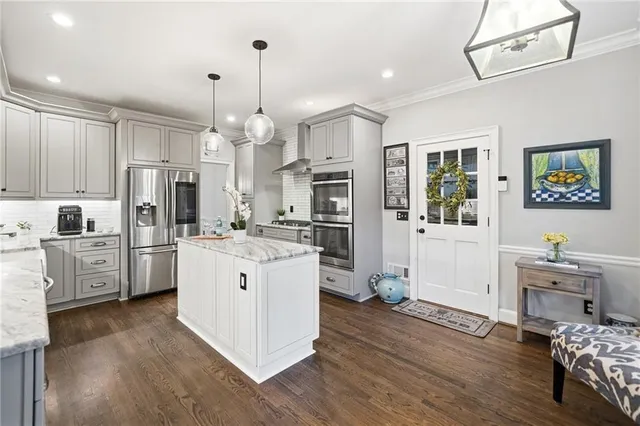 a kitchen with stainless steel appliances a stove a sink dishwasher a refrigerator and white cabinets with wooden floor
