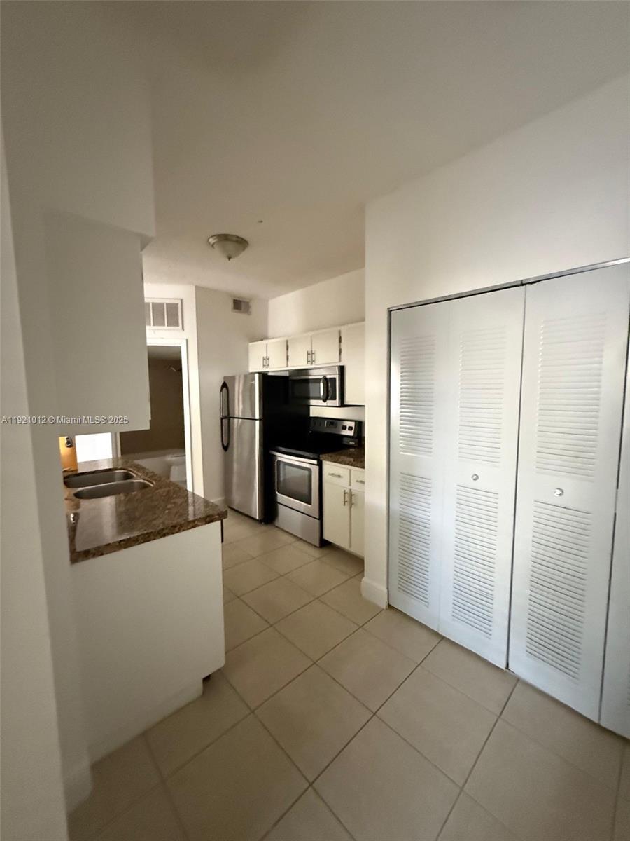 18348 Northwest 68th Avenue, Unit E Hialeah, FL 33015 - Photo 2 of 8 a large kitchen with cabinets and stainless steel appliances