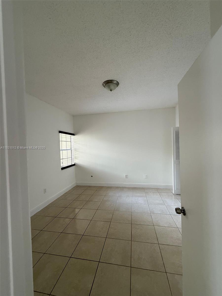 18348 Northwest 68th Avenue, Unit E Hialeah, FL 33015 - Photo 8 of 8 a view of an empty room and window