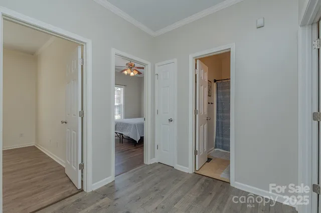 a view of an empty room with wooden floor and a bathroom