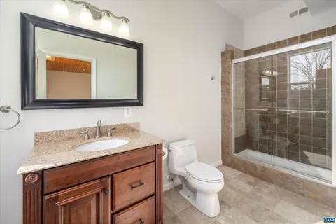 a bathroom with a toilet a sink a mirror and shower