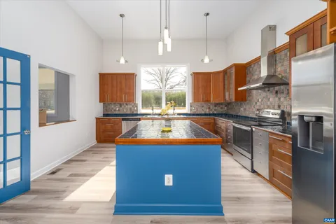 a kitchen with stainless steel appliances granite countertop a sink a stove top oven a counter space and a refrigerator