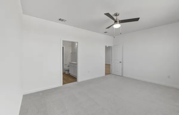 an empty room with ceiling fan and windows
