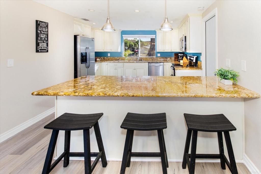 24093 Sargeant Road Ramona, CA 92065 - Photo 10 of 57 a kitchen with stainless steel appliances kitchen island a table chairs in it and wooden floors