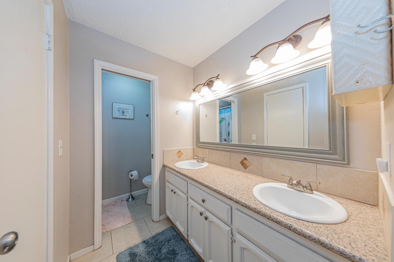 47165 Modoc Road Coarsegold, CA 93614 - Photo 18 of 33 a bathroom with a granite countertop sink double and a mirror