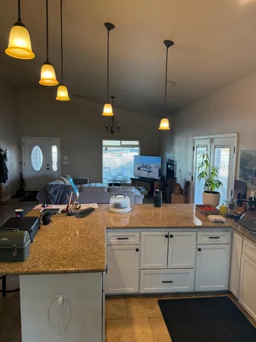 a kitchen with kitchen island granite countertop a stove a sink a counter top space a dining table and chairs