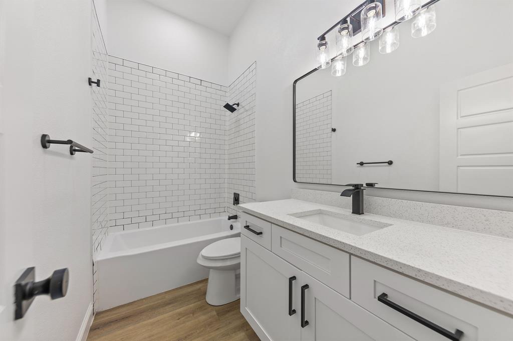 1247 Bonham Street Paris, TX 75460 - Photo 14 of 18 a bathroom with a granite countertop bathtub sink vanity mirror and toilet