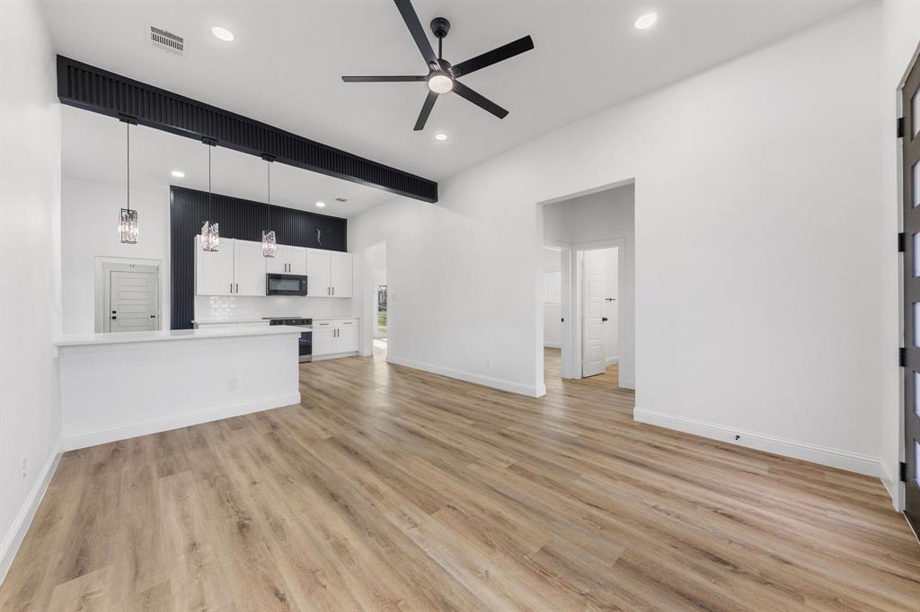 1247 Bonham Street Paris, TX 75460 - Photo 3 of 18 a view of a kitchen with wooden floor and a ceiling fan