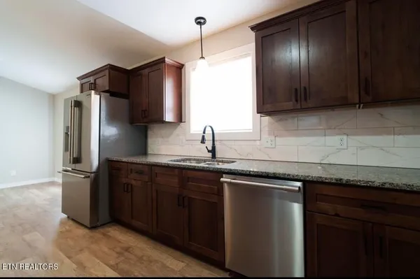 a kitchen with granite countertop a sink cabinets and stainless steel appliances
