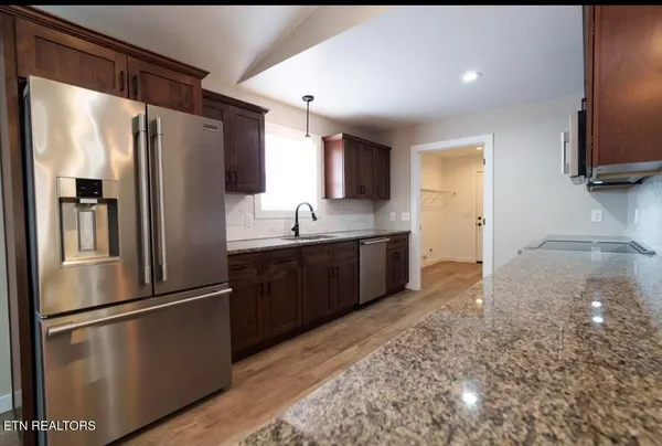 a kitchen with stainless steel appliances granite countertop a refrigerator a sink a stove and oven