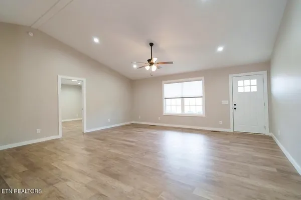 a view of an empty room with window and wooden floor