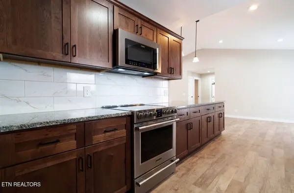 a kitchen with stainless steel appliances granite countertop a stove and a microwave