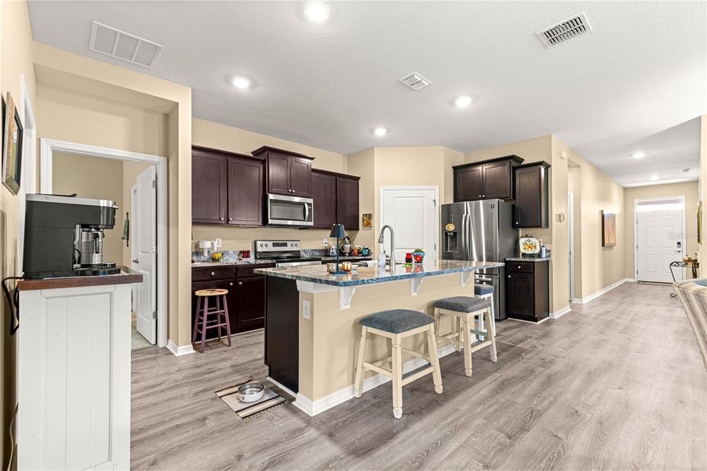 6365 Southwest 88th Loop Ocala, FL 34476 - Photo 11 of 35 a kitchen with a refrigerator a stove top oven a sink dishwasher and wooden cabinets with wooden floor