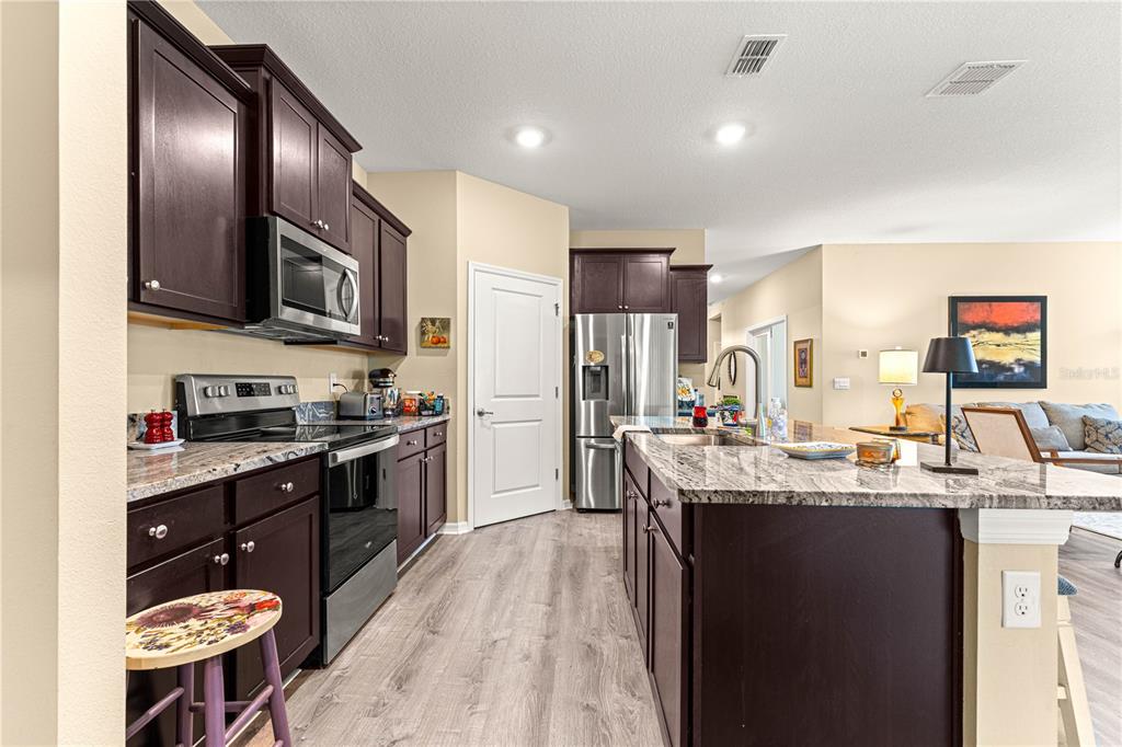 6365 Southwest 88th Loop Ocala, FL 34476 - Photo 13 of 35 a kitchen with stainless steel appliances kitchen island granite countertop a sink stove and cabinets